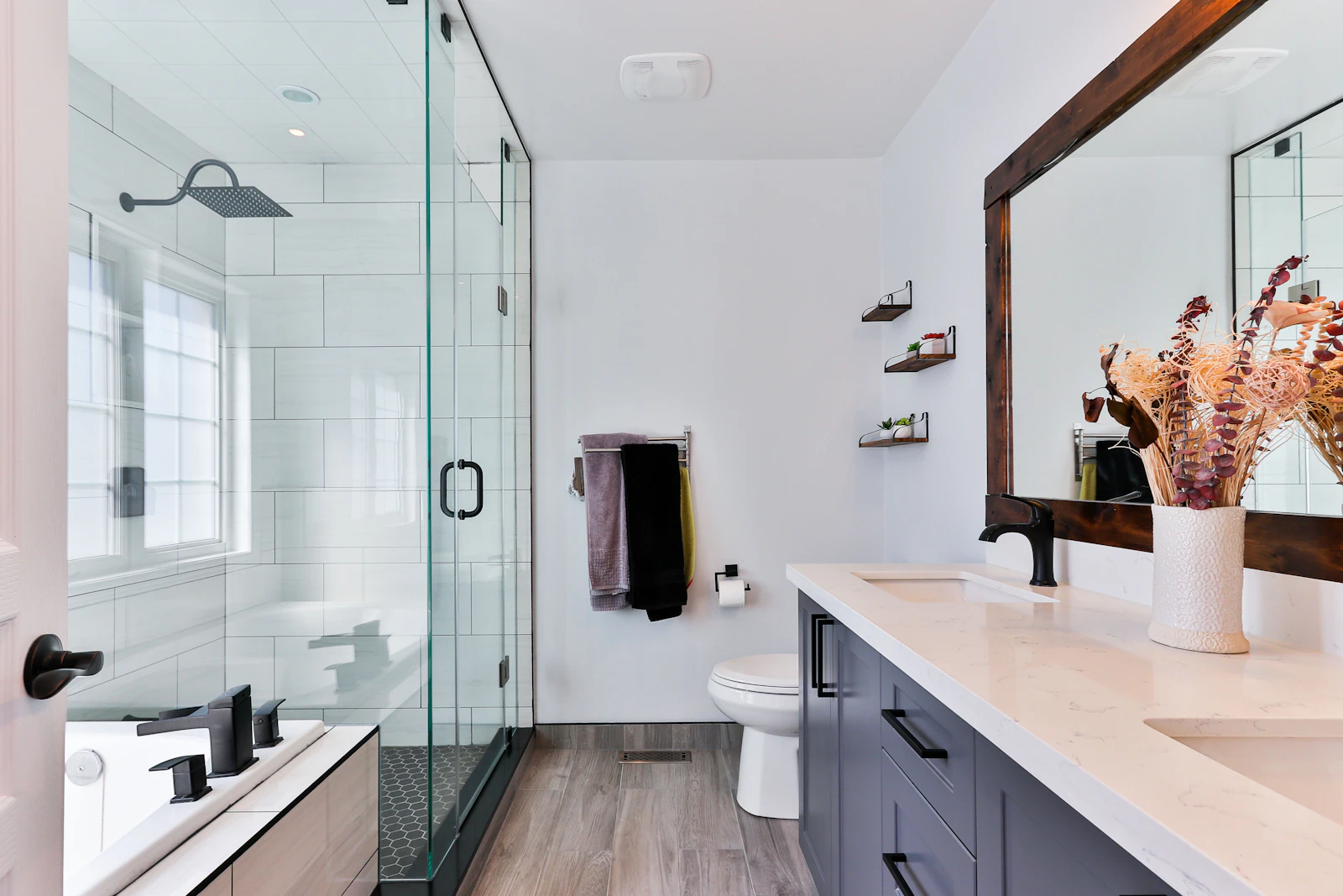 A bright domestic bathroom with a shower, bath, window and extractor fan